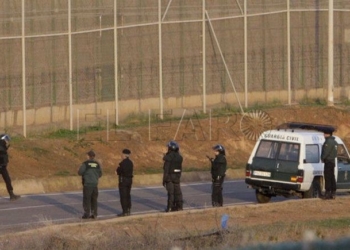 GRA020. MELILLA, 02/12/2014.- Varios subsaharianos permanecen encaramados en la valla de Melilla por la zona cercana al paso fronterizo de Barrio Chino, que está cortado al tránsito desde que a las siete de la mañana se hayan registrado dos intentos de entrada simultánea de dos grupos, con más de medio millar de inmigrantes. EFE/F. G. Guerrero