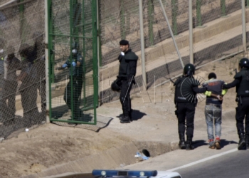 GRA055 MELILLA M 13/8/2014.- Dos de los inmigrantes encaramados a la valla de Melilla desde esta madrugada se han bajado de la verja y han sido entregados a Marruecos. Los dos subsaharianos han descendido por una de las escaleras colocadas por la Guardia Civil y, posteriormente, han sido entregados a las autoridades marroquíes por una de las puertas de acceso de la valla.El resto de subsaharinos, entre 60 y 70, permanecen subido en la parte alta del vallado, a una altura de seis metros, visiblemente cansados, tras siete horas.A ambos lados del perimetro, tanto en el lado español como en el marroquí, hay un fuerte despliegue policial.EFE/Francisco G. Guerrero