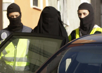 Una de las mujeres detenidas en Melilla, vestida con "niqab", una prenda de color negro que cubre por completo el cuerpo y el rostro de la mujer, a la salida de la vivienda donde ha sido apresada en la ciudad autónoma, donde se han producido otras dos detenciones, un hombre y una menor, en el marco de una operación contra una red de captación y envío de mujeres a la organización terrorista yihadista DAESH. EFE/F. G. Guerrero