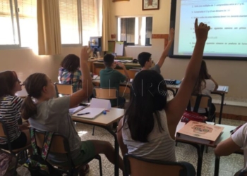 Unos niños atendiendo en clase a su maestra.