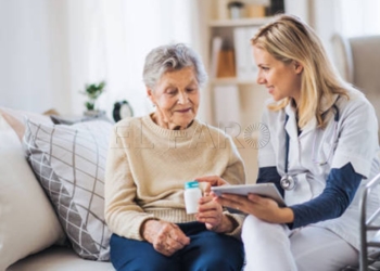 A young health visitor with tablet explaining a senior woman how to take medicine and pills.