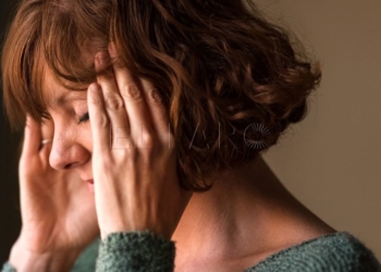 Close-up shot of a woman suffering from a headache and rubbing her temples  at home