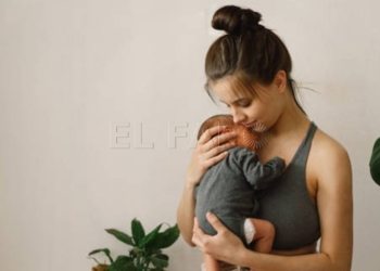 Mother holds and hugs her newborn baby son at home. Happy infant and mom. Mother's day concept