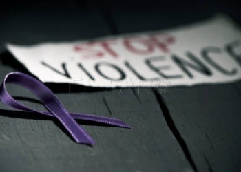 a purple ribbon for the awareness about the unacceptability of the violence against women and the text stop violence on a piece of paper, on a dark gray rustic wooden surface