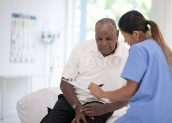 An African senior gentleman speaks with his doctor during a routine check-up in the doctors office