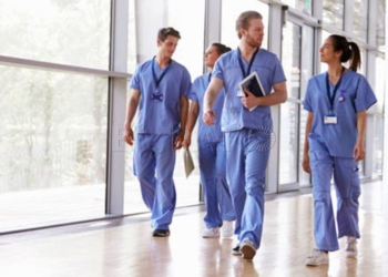 Four healthcare workers in scrubs walking in corridor